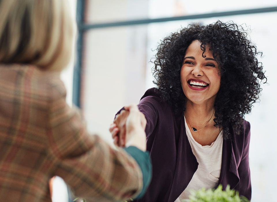 two business women shake hands at a meeting